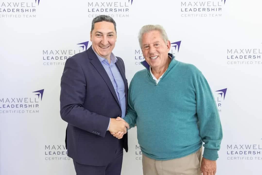 Sebastian Buși dând mâna cu John C. Maxwell, la International Maxwell Conference
