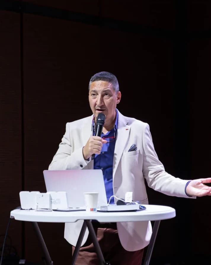 Sebastian Buși vorbind pe scenă, cu microfonul în mână
