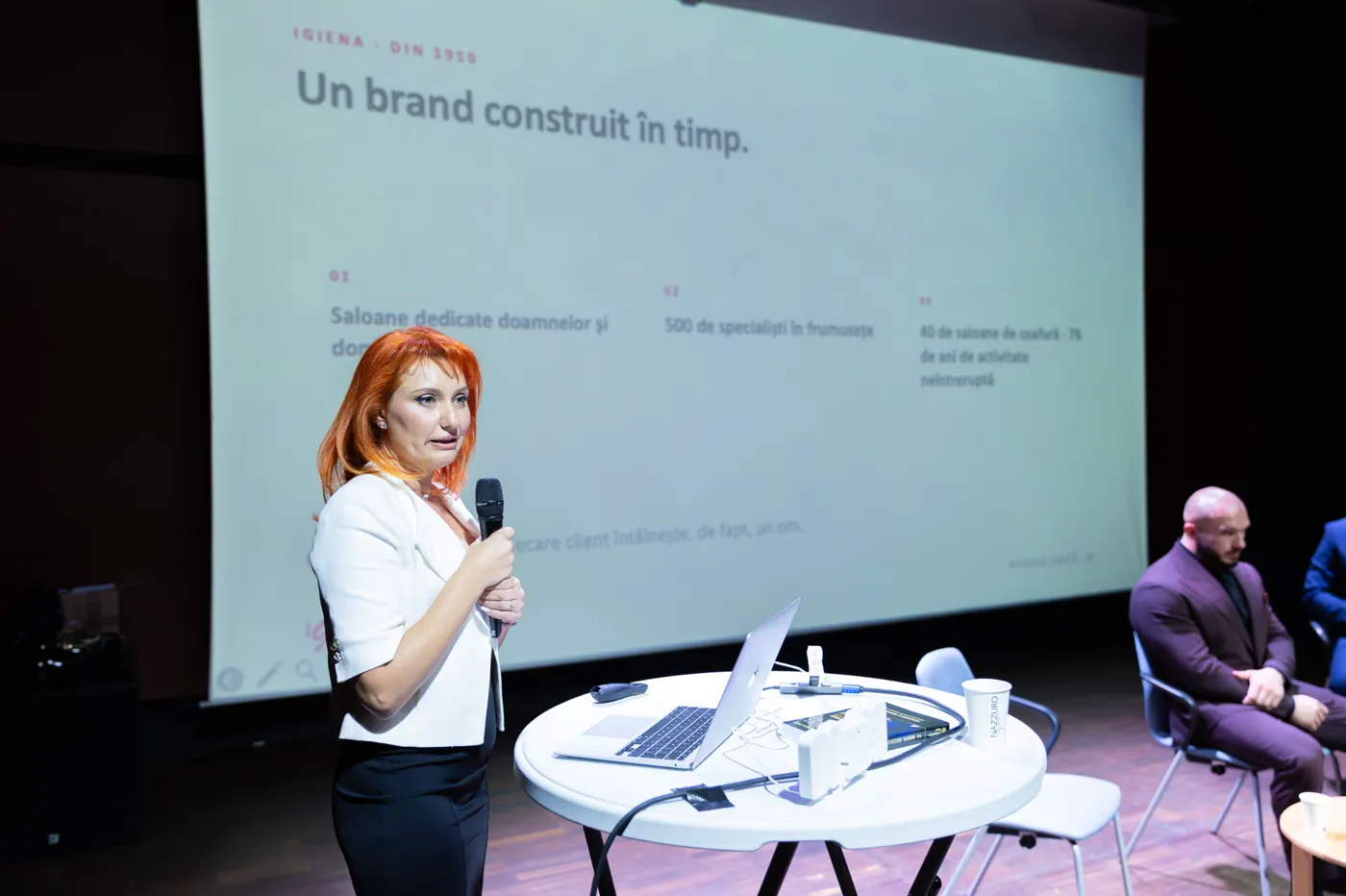 Ramona Diniță prezintă pe scenă, lângă un slide intitulat „Un brand construit în timp”.